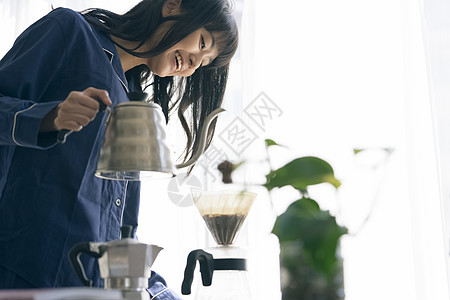 拿着水壶冲泡咖啡的年轻女子图片