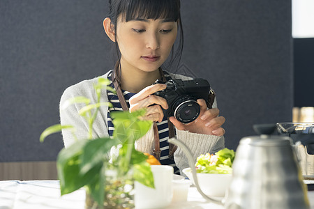拿着相机拍食物照片的女青年图片