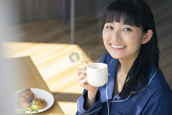 早餐拿着咖啡开心的年轻女子图片