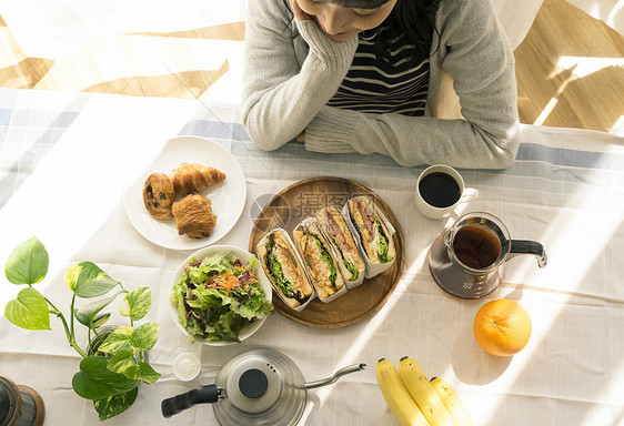 年轻女子微笑看着餐桌上的早午餐图片