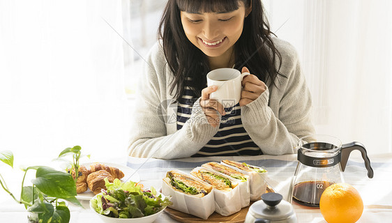 年轻女子拿着咖啡开心的看着美食图片