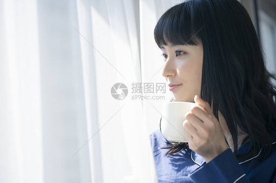 窗边拿着咖啡微笑的女青年图片