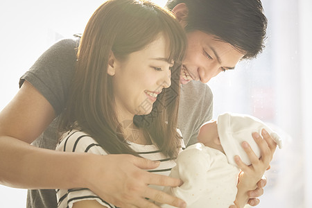 微笑婴儿抱着孩子开心的年轻夫妇背景
