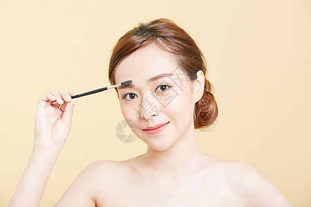 使用眉刷化妆的成年女性图片