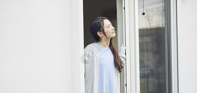 靠在窗边的居家女性图片