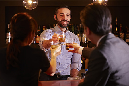 酒吧里的外国调酒师和客人一起碰杯图片