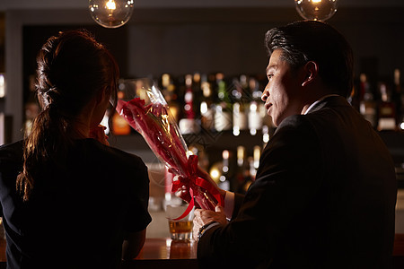一流坐花朵男人和女人在酒吧喝酒图片