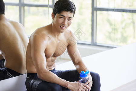 健身房镜子年轻人在健身房喝水休息背景