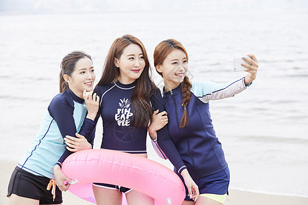 三个年轻女人在海边沙滩上自拍合影图片素材