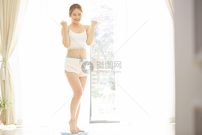 站在体重秤上开心的女子图片