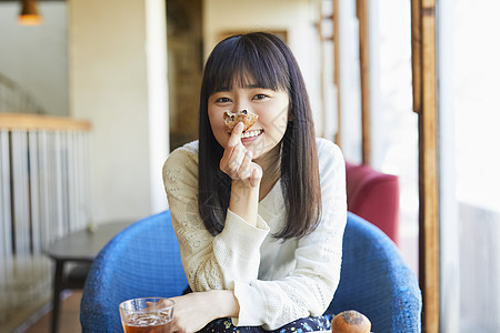 咖啡馆吃着面包微笑的年轻女子图片