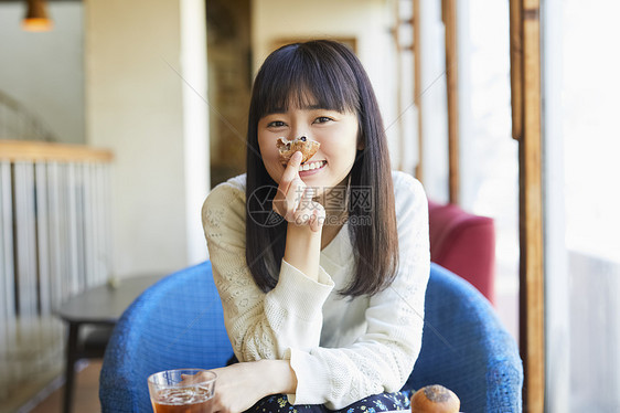 咖啡馆吃着面包微笑的年轻女子图片