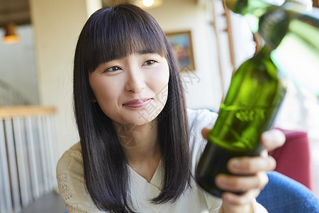 拿着瓶装啤酒微笑的年轻女子图片