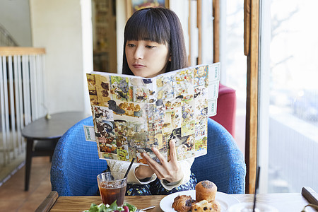 年轻女子在咖啡馆看漫画书放松图片