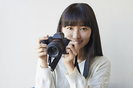 美容女郎拿着相机微笑的年轻女子背景
