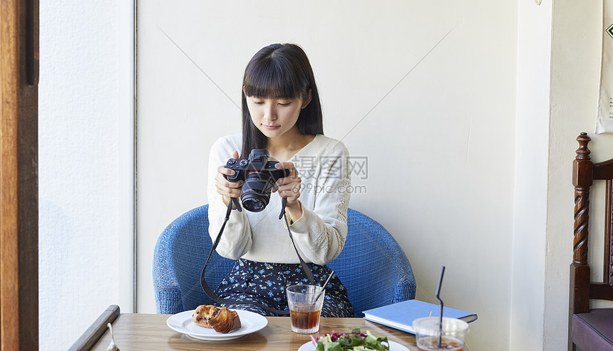 咖啡馆拿着相机拍食物的女子图片