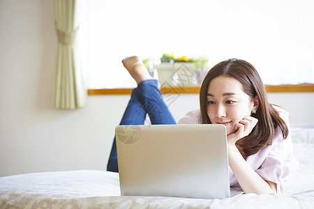 年轻女人躺在床上看电脑图片