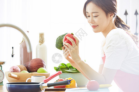 厨房里料理拿着蔬菜的年轻女子图片