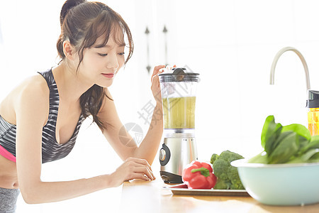 运动女孩在厨房榨蔬菜汁图片