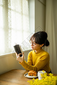 看书吃早餐的眼镜女孩图片