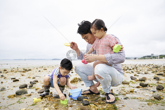 在海边捡石子的一家人图片