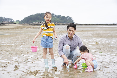 在海边捡石子的一家人 图片