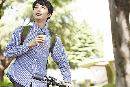 拿着咖啡推着自行车的青年男子图片