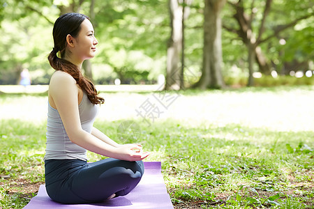 公园里坐在瑜伽垫上的女子图片