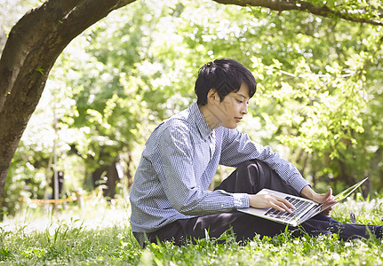公园里使用笔记本电脑的青年男子图片