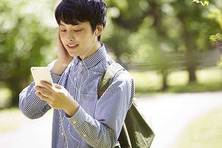 室外低头看着手机的青年男子图片