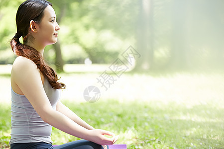 公园草坪瑜伽垫上的女子图片