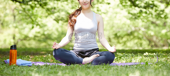 草地上盘腿坐着的瑜伽女性特写图片