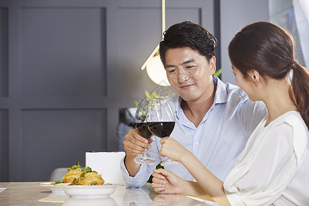 年轻夫妻吃西餐喝红酒背景图片