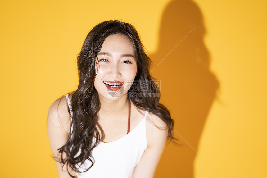 黄色背景微笑的年轻女子图片