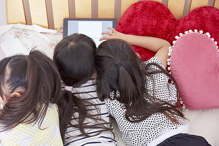 小朋友趴在床上玩平板电脑图片素材