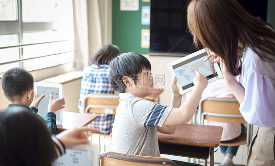 小学生在老师的指导下学习平板电脑使用知识图片