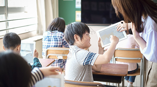 小学生在老师的指导下学习平板电脑使用知识图片