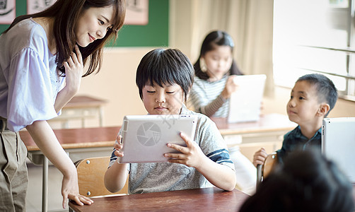 小学生在老师的指导下学习平板电脑使用知识图片