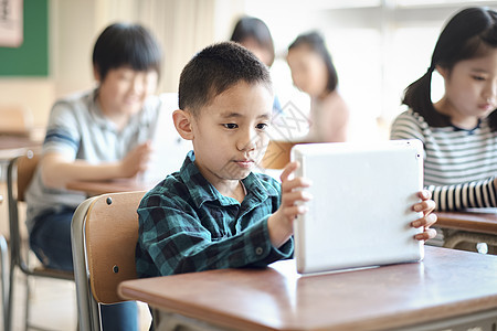 小学生在老师的指导下学习平板电脑使用知识背景图片