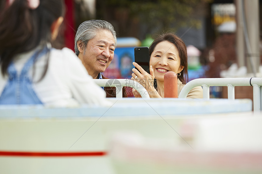 祖父母陪孙女在游乐园里拍照图片