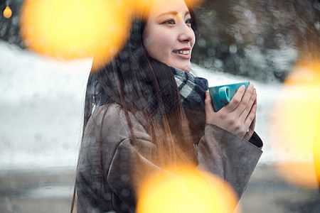 年轻轻松彩灯享受在雪的妇女茶时间图片