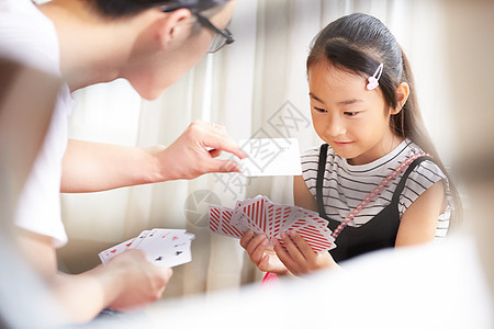 室内爸爸陪女儿愉快玩纸牌图片