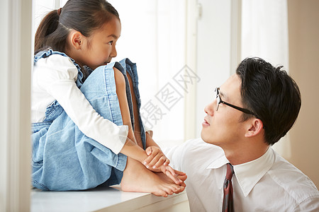 窗台上的男人爸爸看着坐在窗台上的女儿背景