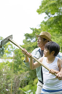 户外乡村爷爷教男孩用锄头图片