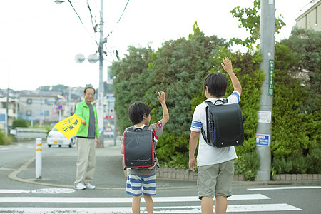 老年人指导小学生去学校过马路背景图片