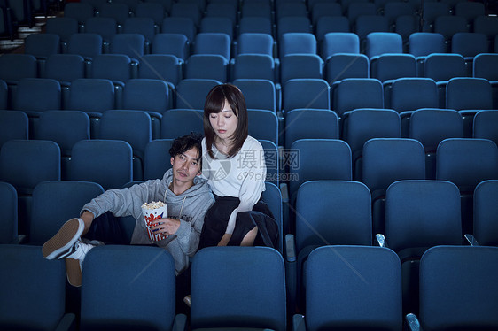坐下亲密男人们观看电影的观众在电影院图片