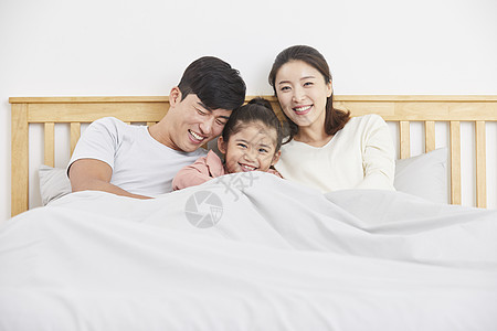 幸福的一家三口在床上休息图片