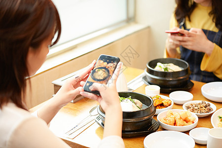 年轻女人们在餐厅吃美食拍照图片