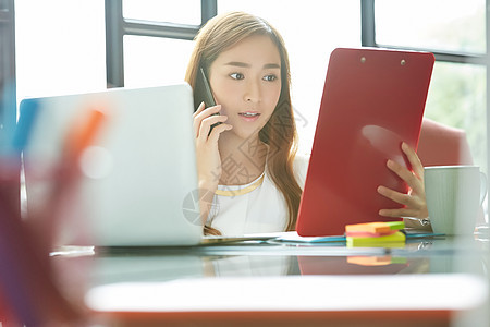 使用便携电脑的女人在书桌上打电话图片