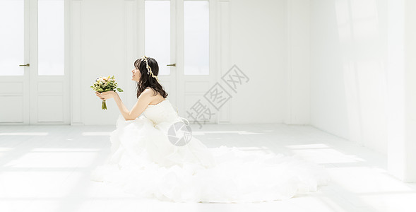 新娘拿着手捧花蹲坐在地上图片